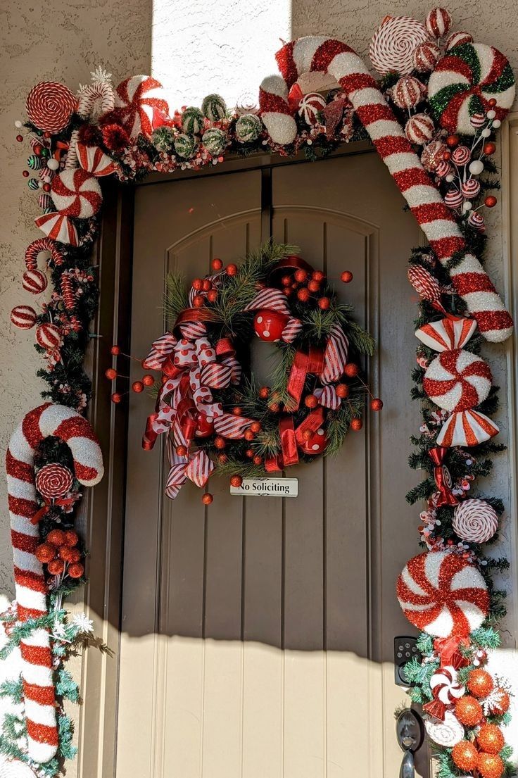 a wreath with candy canes and decorations on the front door is decorated for christmas