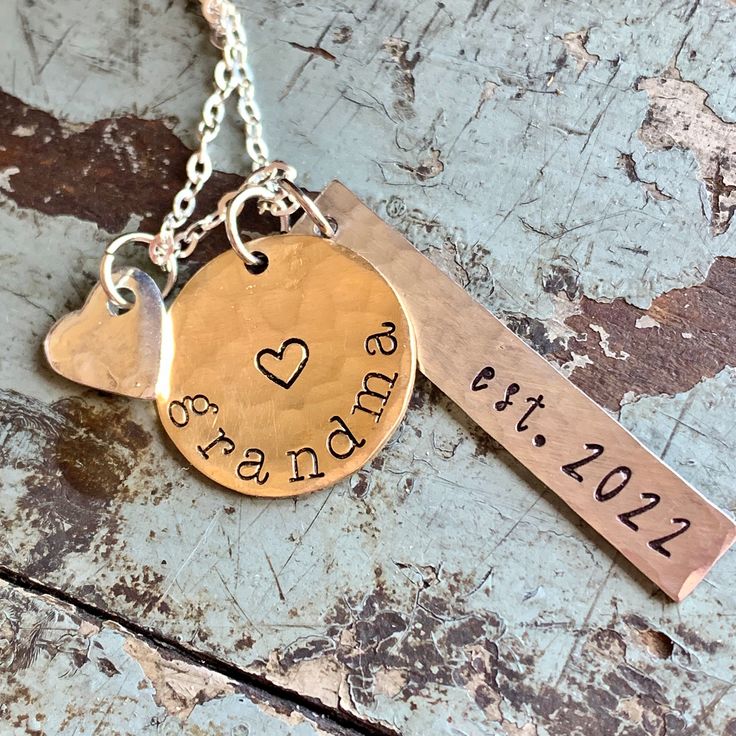 "New grandma personalized gift. Show your grandparent pride with this \"established\" grandma necklace. 1 1/4\" handstamped silver tag in script font \"est.\" with date you became (or will become) a grandma. Has a brushed satin, hammered finish. Charm is silver alkeme', which is a metal alloy that won't tarnish and is very durable. It is hypo-allergenic and nickel free and made in the USA. 5/8\" brass disc stamped \"grandma\" or any name you prefer... nana, mama, granny, etc. 1/4\" silver heart Hand Stamped Name Necklace For Mother's Day, Hand Stamped Silver Name Necklace For Mother's Day, Silver Hand Stamped Name Necklace For Mother's Day, Silver Hand Stamped Necklace For Mother's Day, Silver Hand Stamped Name Necklace For Anniversary, Hand Stamped Round Pendant Name Necklace For Mother's Day, Hand Stamped Sterling Silver Name Necklace For Anniversary, Mother's Day Hand Stamped Nameplate Necklace, Mother's Day Nameplate Hand Stamped Necklace