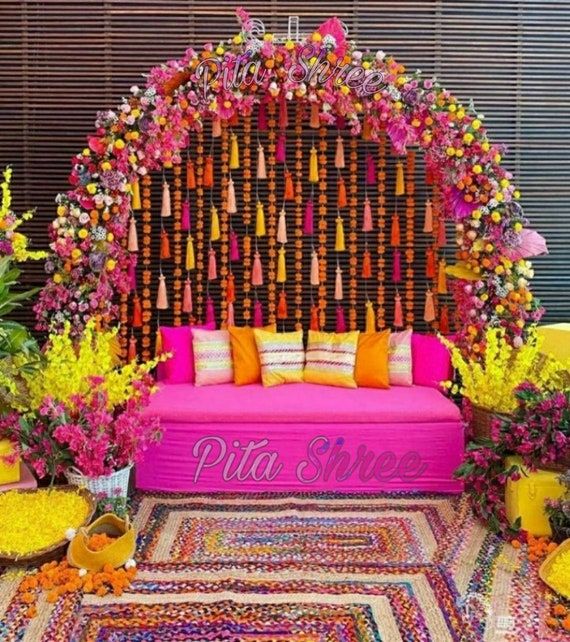 a pink couch sitting in front of a flower covered wall with lots of flowers on it