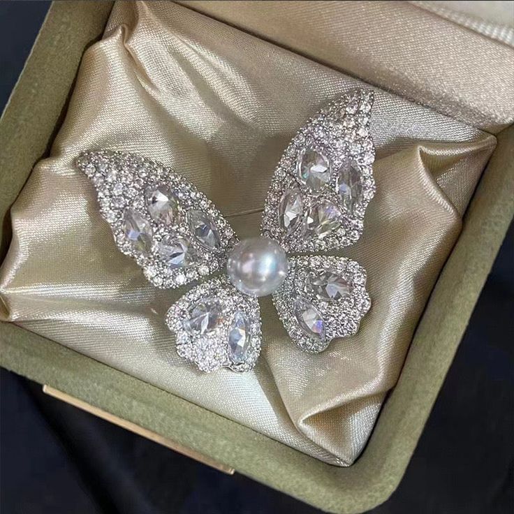 Embrace elegance with our Butterfly Brooch, featuring a radiant 8-9mm freshwater pearl nestled among sparkling cubic zirconia. Available in gold and silver finishes, this exquisite piece adds a touch of sophistication to any outfit. A perfect gift to symbolize transformation and beauty Material: Gold plated on brass, cubic zirconia, and freshwater pearls Pearl Size: 8-9mm Note: Our jewelry is handmade. Naturally formed shapes of freshwater baroque pearls may vary. The actual product may be sligh White Diamond Wedding Brooches, Exquisite White Wedding Brooches, Luxury Diamond White Brooches For Wedding, Elegant Diamond White Brooches For Wedding, Elegant Diamond White Wedding Brooches, Elegant Brooch With Diamond Accents As Gift, Elegant Diamond Accented Brooch Gift, Elegant Diamond Accented Brooches As Gifts, Elegant Silver Diamond Brooch