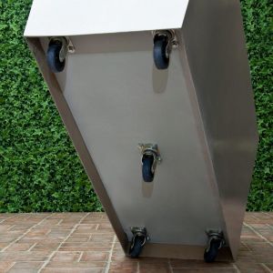 a metal box sitting on top of a tile floor next to a green wall with plants