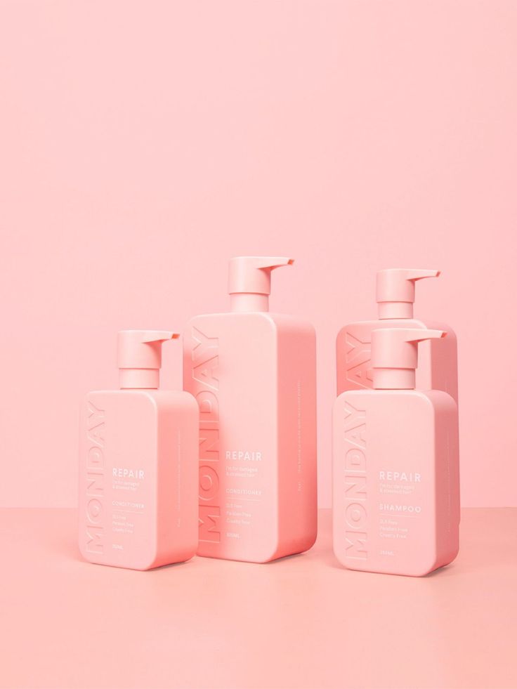 three bottles of soap on a pink background