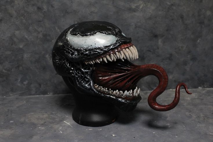 a close up of an alien head on a black object with white teeth and mouth