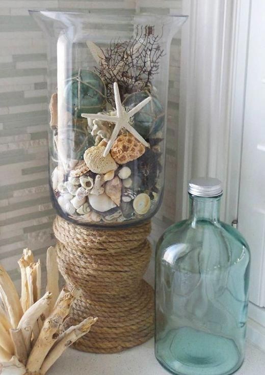 a glass jar filled with shells and starfish on top of a table next to a bottle