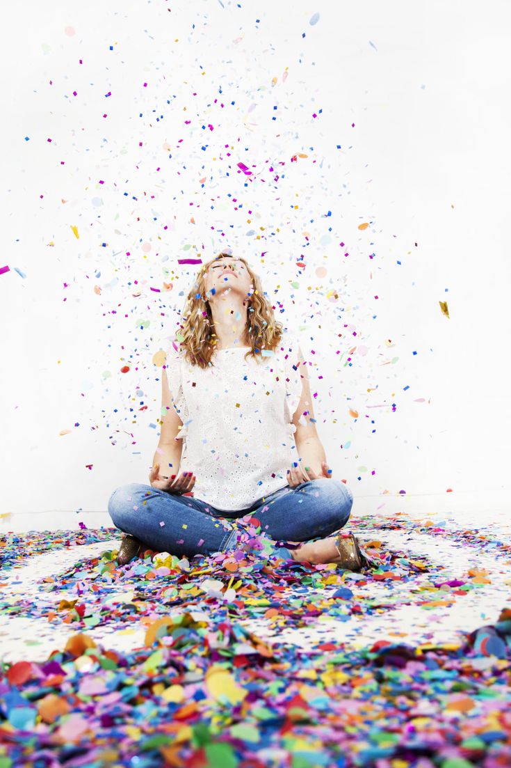 a woman sitting on the floor surrounded by confetti