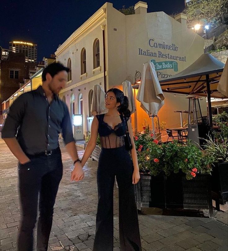 a man and woman standing in front of a building