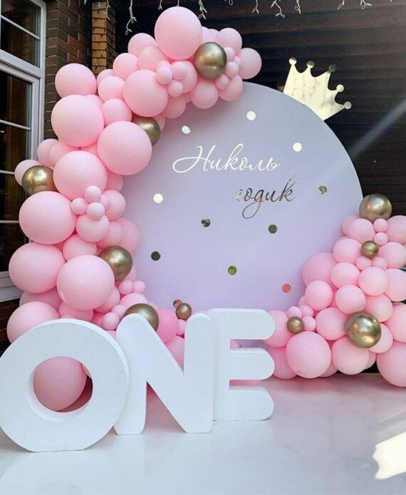 a large balloon arch with pink and gold balloons in the shape of a wreath on top of it