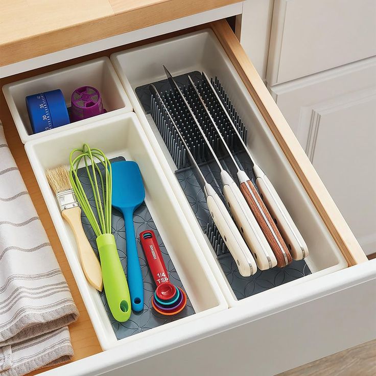 an organized drawer with utensils and other kitchen items in it on the counter