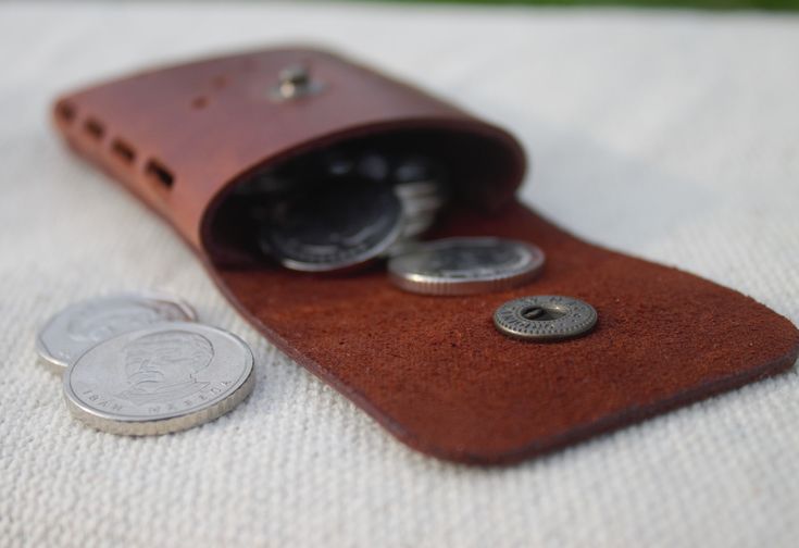 a leather case with two coins in it and one coin is laying next to it