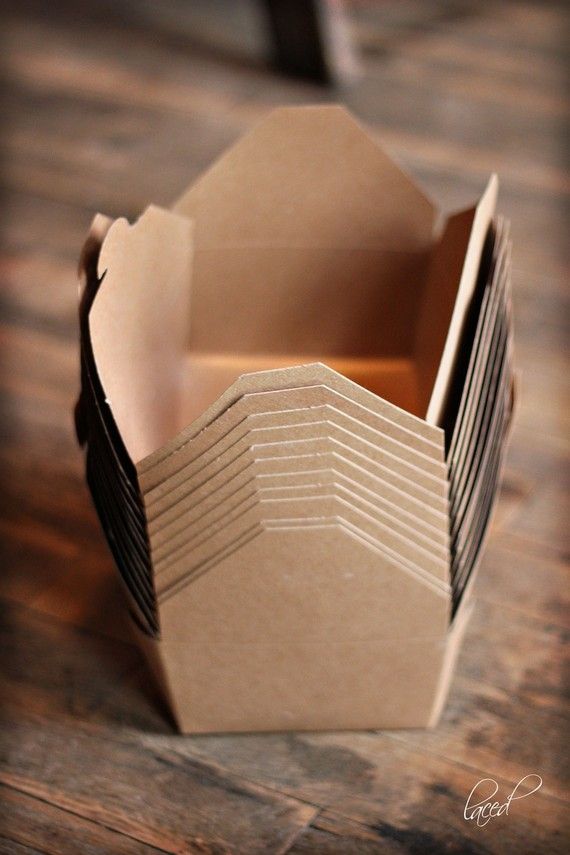 an open brown box sitting on top of a wooden table filled with lots of paper