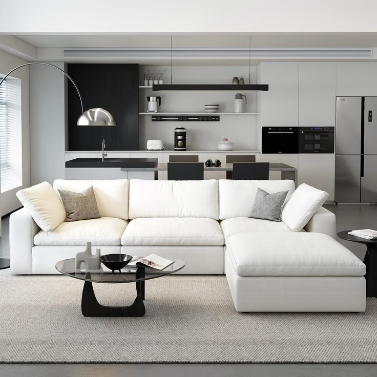 a living room filled with furniture and a glass table in front of a kitchen area