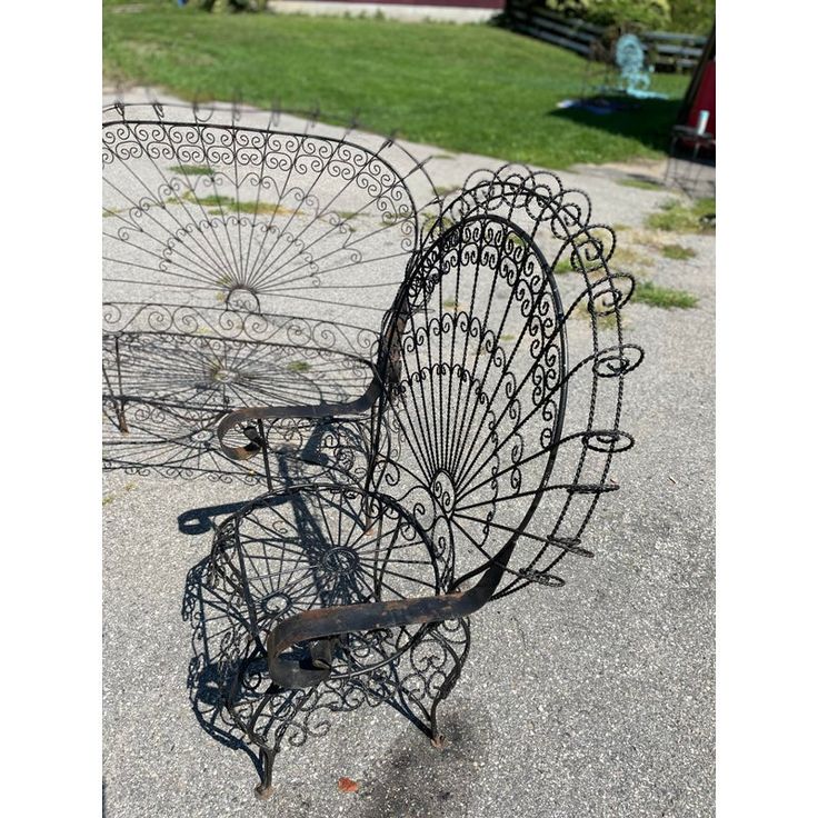 two metal chairs sitting next to each other on top of a cement ground with grass in the background