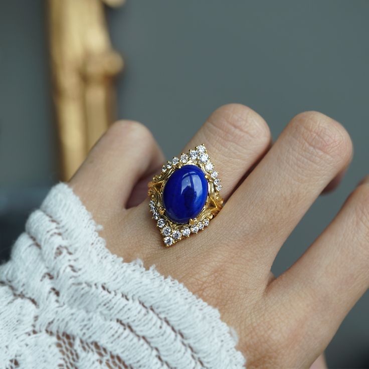 Read about our payment plans before proceeding. Elevate your elegance with the Heavenly Lapis Lazuli Ring, a stunning creation that marries the deep, celestial beauty of lapis lazuli with the timeless brilliance of white diamonds. The ring is adorned with a big natural lapis lazuli framed with natural white diamonds. Designed with a feminine antique frame, this exquisite ring is perfect for those who seek a blend of classic sophistication and modern allure. Crafted by skilled hands, this ring is available in your choice of 14K and 18K yellow gold, rose gold, and white gold. All orders come in our Tippy Taste ring box. This ring is handmade and designed in NYC. 14K or 18K solid gold Natural oval lapis lazuli, 14*10mm, approx. 5.81ct 22 Natural round diamonds. SI clarity, GH color, 0.42ct to Antique Frame, Lapis Lazuli Ring, Antique Frames, White Diamonds, The Deep, Ring Box, Gold Rose, Diamond White, Lapis Lazuli