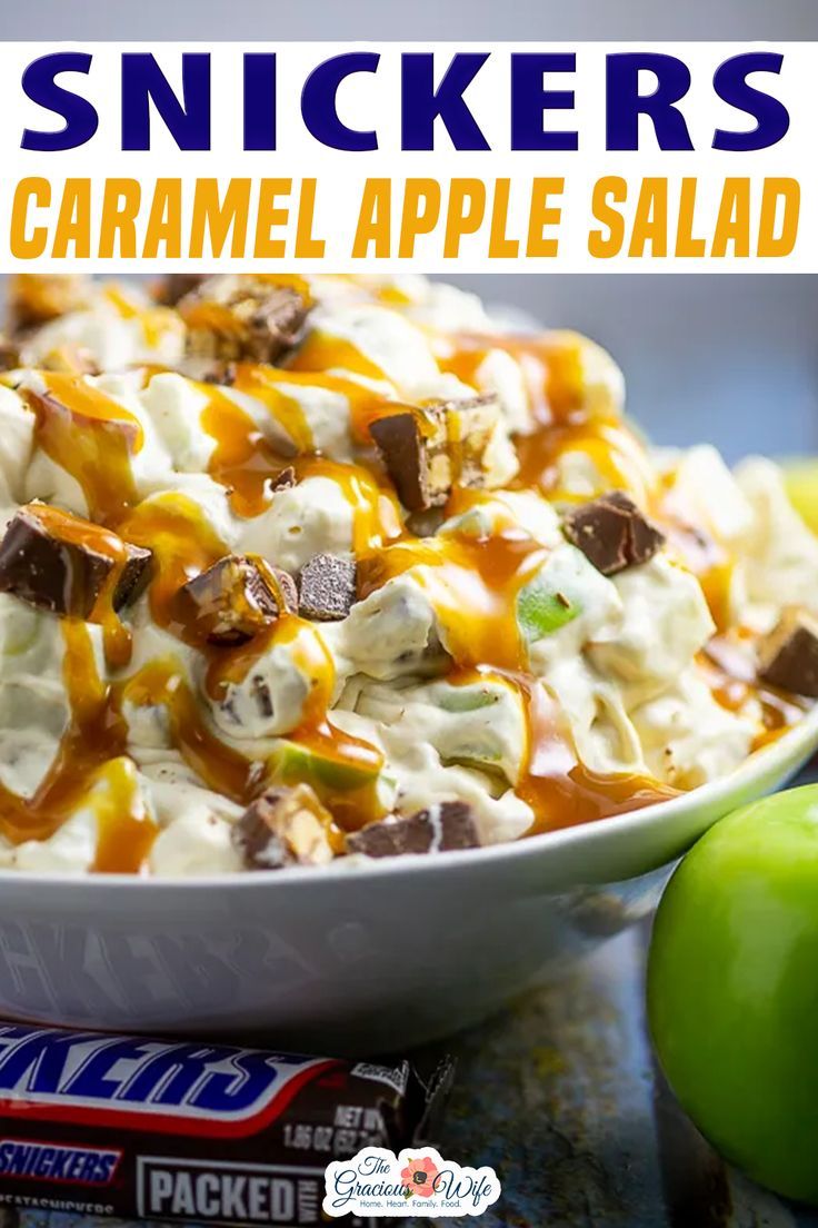 a bowl filled with caramel apple salad next to an apple and two candy bars