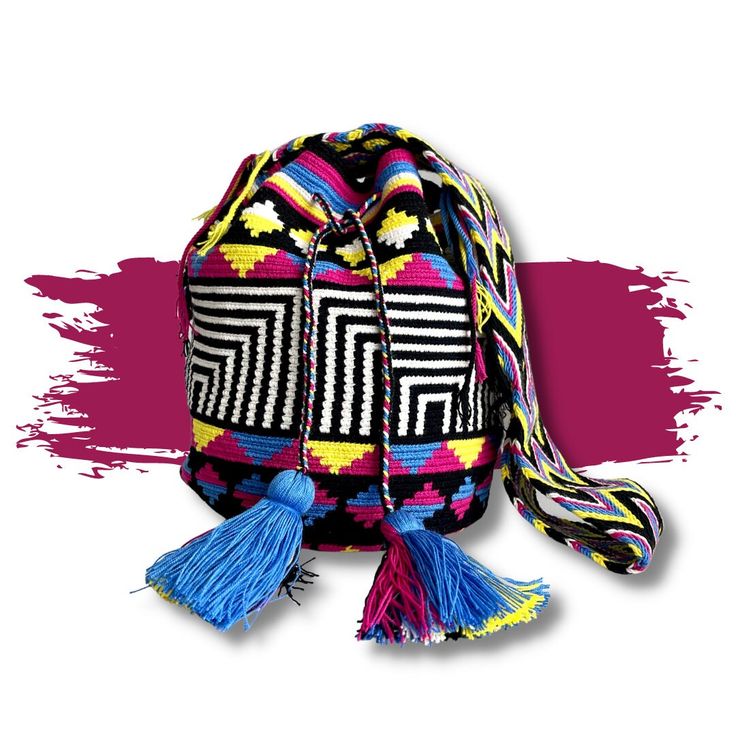 a multicolored bag with tassels on the front and side, sitting against a pink background