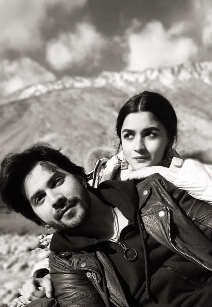 black and white photograph of two people sitting in the desert with mountains in the background