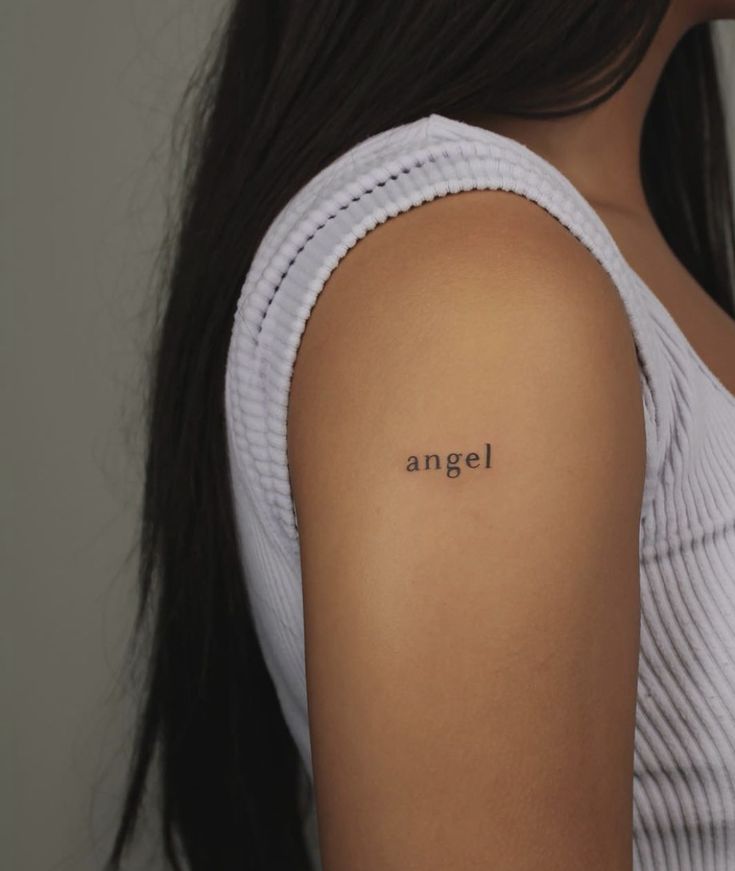 a woman with an angel tattoo on her upper arm and the word'angel'written in black ink