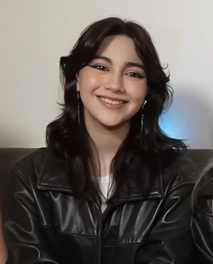 a woman sitting on top of a couch wearing a black leather jacket