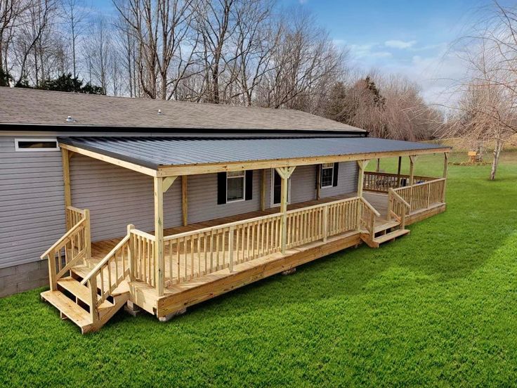 a small house sitting on top of a lush green field next to a wooden deck