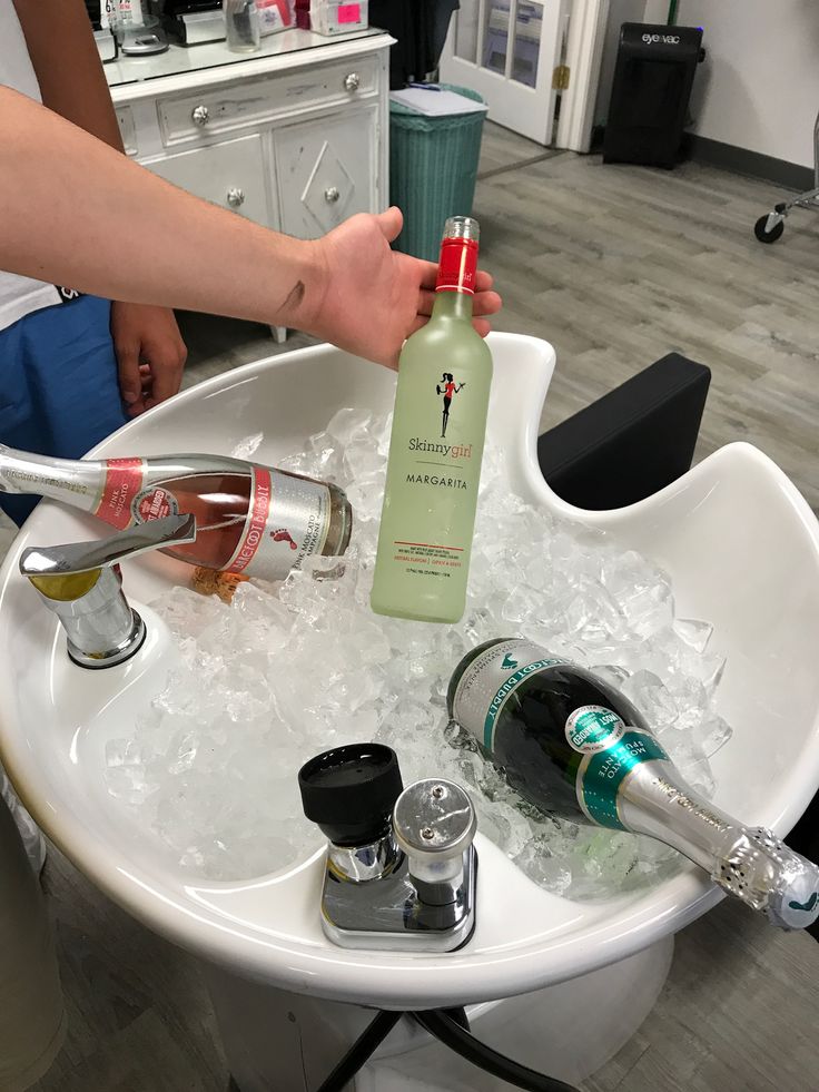 a person is holding a bottle of alcohol in an ice bucket with other bottles on it