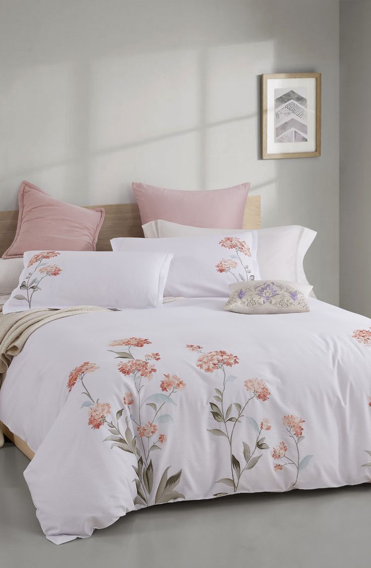 a bed with pink comforters and pillows in a room next to a painting on the wall