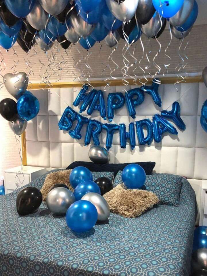 a bed with blue and silver balloons on the headboard, and a happy birthday sign above it