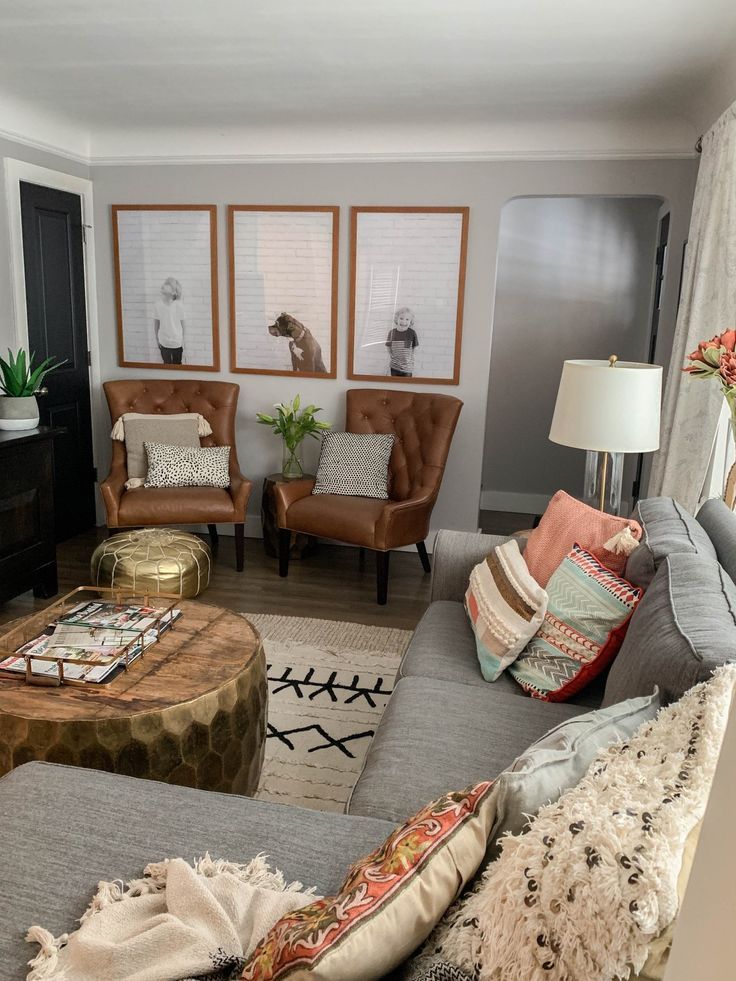 a living room with couches, chairs and pictures hanging on the wall above them