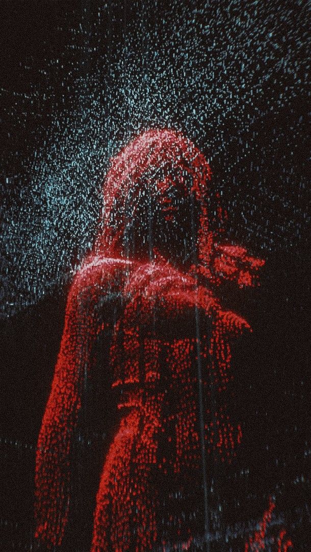 a person standing in the rain with red lights on their face and arms, behind them is a black background