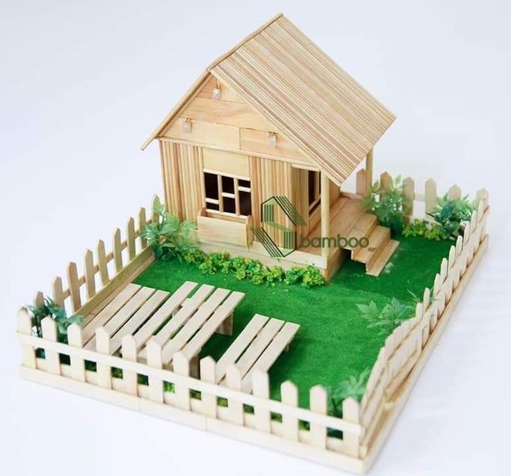 a small wooden house sitting on top of a lush green field next to a fence