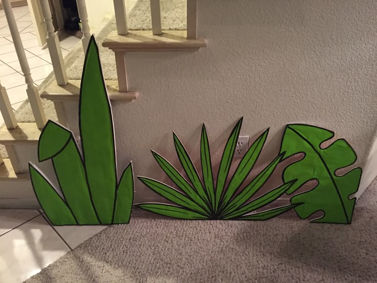 a green plant sitting on top of a carpeted floor next to a stair case