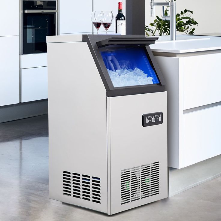 a small ice machine sitting on top of a kitchen counter next to a wine glass