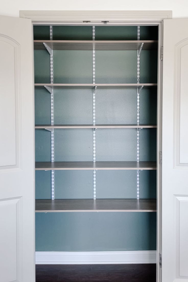 an empty closet with blue walls and shelves