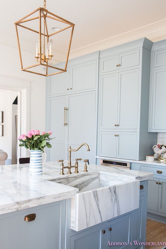 a kitchen with marble counter tops and gold faucets on the sink, along with blue cabinets