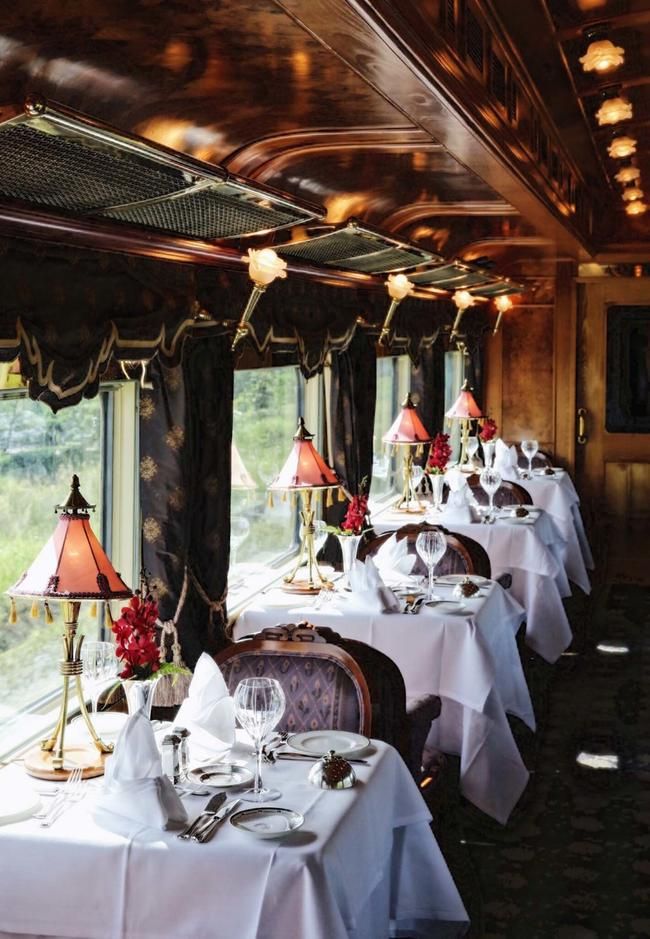 a dining car on a train with white tablecloths and place settings set for four