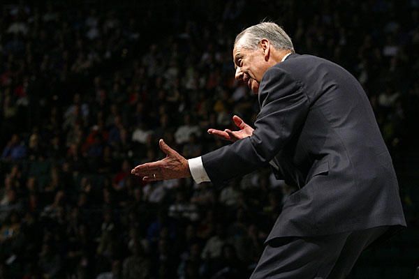 a man in a suit and tie standing on a stage with his hands out to the crowd