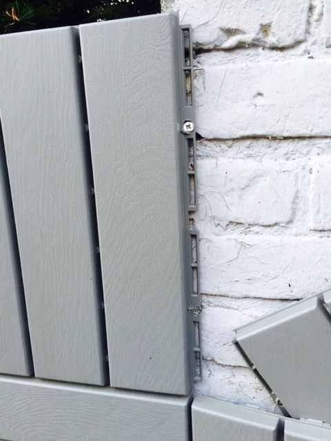 a white brick wall with grey metal bars on it's sides and a planter in the background