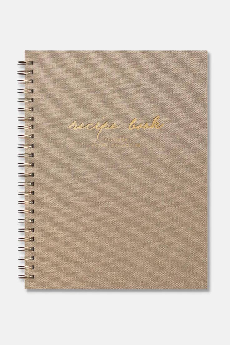 a notebook with the words recipe book written in gold foil on it, sitting on top of a white surface