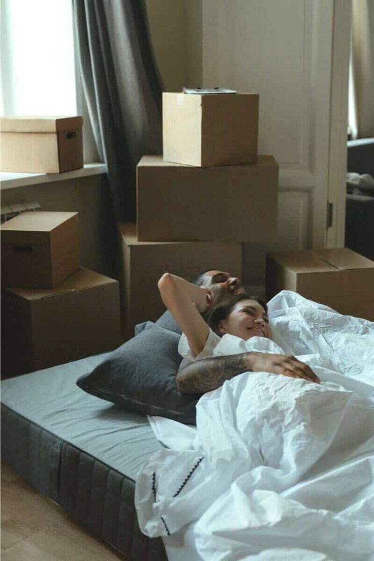 a woman laying on top of a bed next to boxes