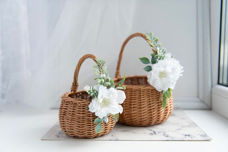 two wicker baskets with white flowers in them