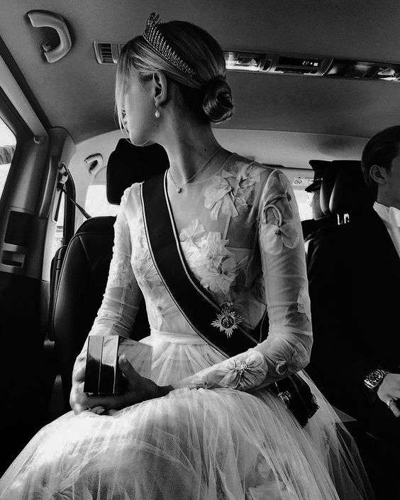 a woman sitting in the back seat of a car wearing a tiara and dress