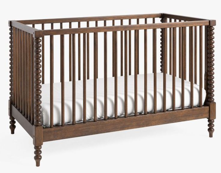 a wooden crib with white sheets on the bottom and side rails, against a white background