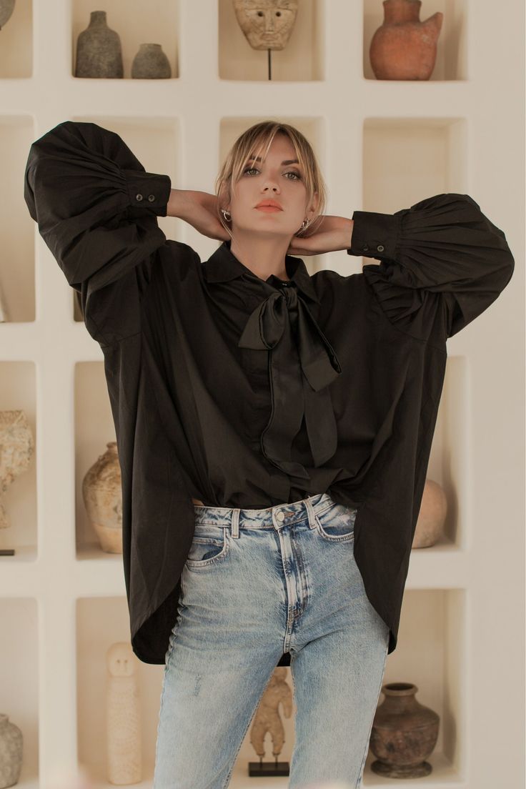 "You will fall in love with this glamorous classic-shirt-reimagined style. Designed with ruched statement puff sleeves and detachable black satin silk tie our chic and sleek Merci cotton poplin shirt offers oversized fit and high low hem that makes it easy to tuck it into jeans, skirts and tailoring. Choose slim-fitting jeans and heeled booties to make this piece the protagonist of your look Comes in three shades: White, Black, Blue -Content: Shirt 100% Organic Cotton, tie 100% Satin Silk -Hand Elf Shirt, Balloon Sleeve Dress, Balloon Sleeve Blouse, Cotton Poplin Shirt, Satin Silk, Fall Shopping, Poplin Shirt, Womens Clothing Sizes, High Low Hem