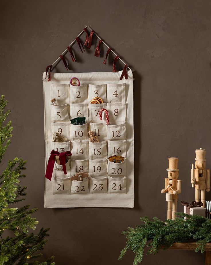 a christmas calendar hanging on the wall next to a tree and other decorations in front of it