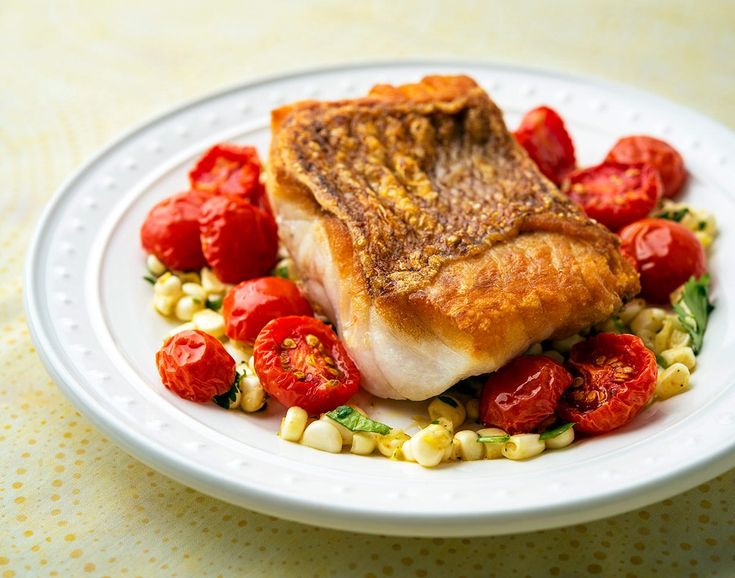 a white plate topped with fish and tomatoes