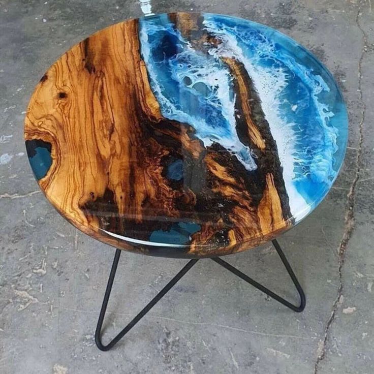 a wooden table with blue and black paint on it's surface, sitting on concrete