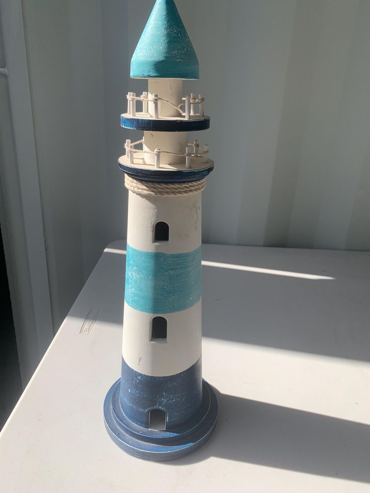 a small white and blue lighthouse sitting on top of a table