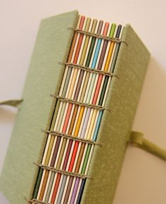 a green book with many colored pencils in it