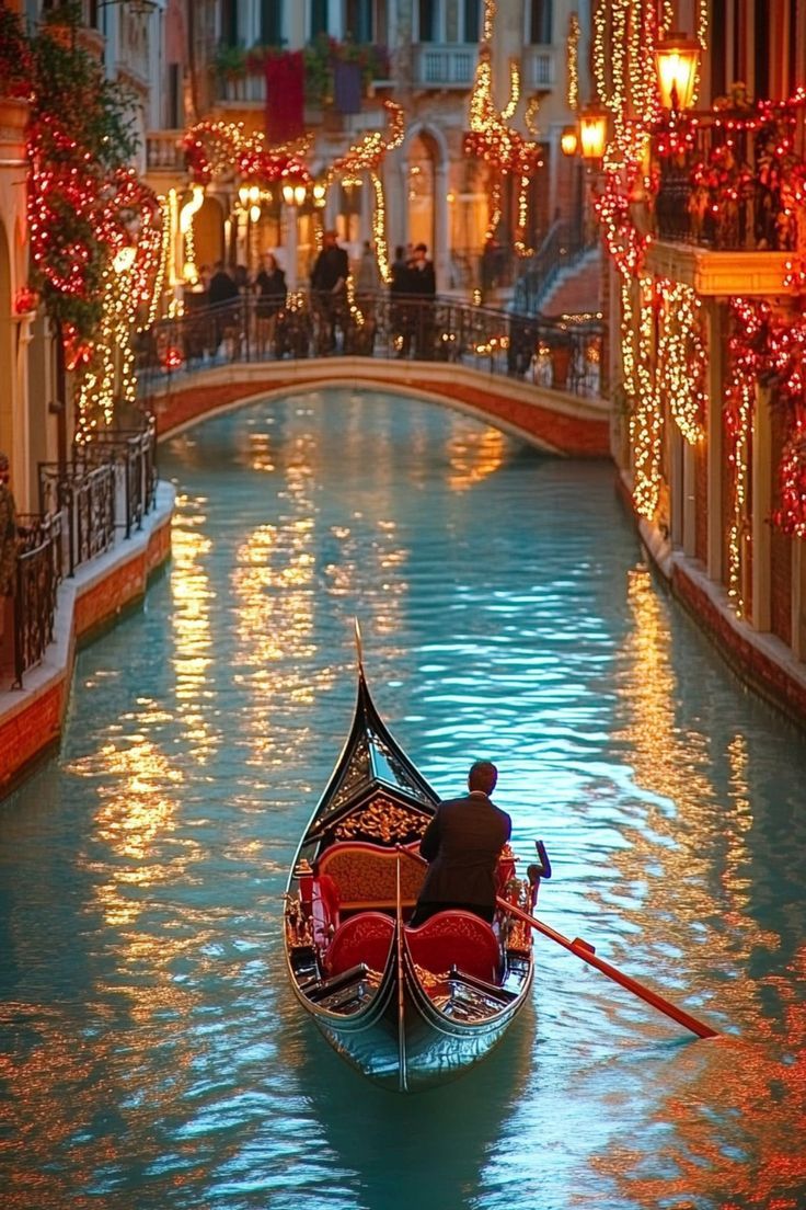 a gondola in the middle of a canal with lights on either side and people riding down it