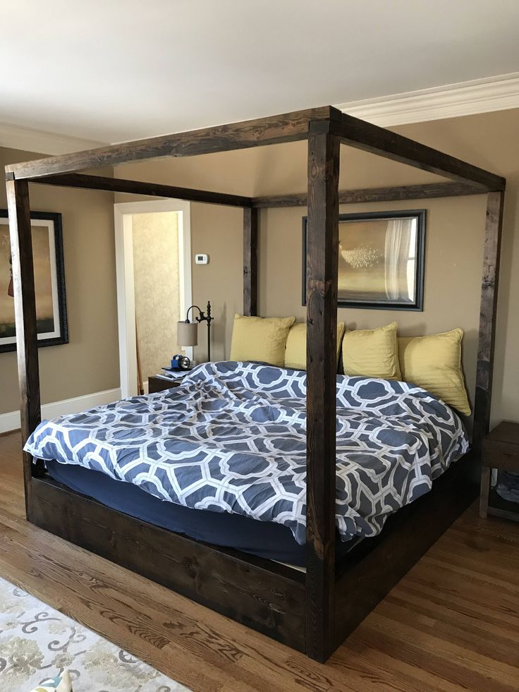 a bedroom with a four poster bed in the middle and wood flooring on the other side