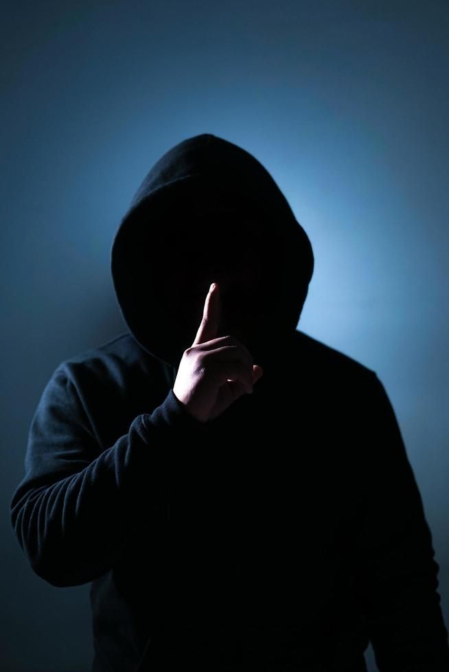 a person in a hoodie is making the middle finger sign with their hand while standing against a dark background